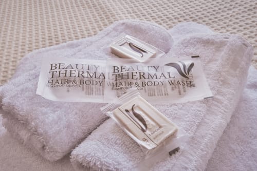 Amenities termali Beauty per capelli e corpo su asciugamani bianchi presso Casa Mia B&B, boutique hotel italiano