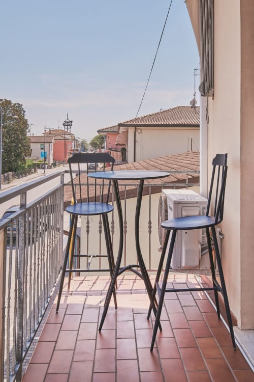Balcone in terracotta con sedute a bar nero che affaccia sui tetti di una cittadina italiana a Casa Mia B&B
