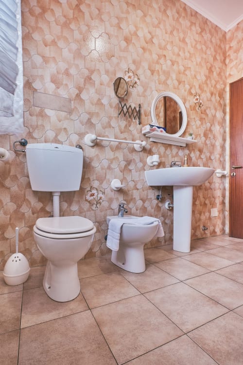 Bagno di Casa Mia B&B con sanitari bianchi, lavabo a colonna e pareti decorate con piastrelle color pesca