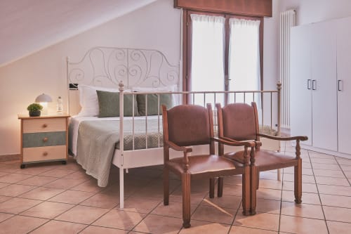 Spaziosa camera familiare a Casa Mia B&B con letto in ferro battuto, sedie in legno, balconate e vista sulla città