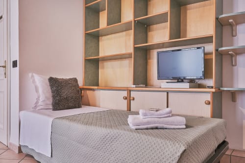 Camera moderna a Casa Mia B&B con letto, scaffali in legno, TV a schermo piatto e pareti rosa in Italia