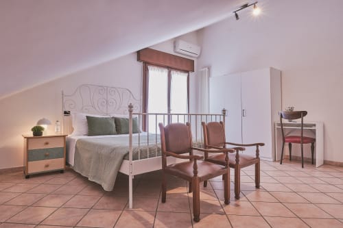 Ampia camera famigliare presso Casa Mia B&B in Italia con balcone, letto in metallo, sedie in legno e vista sulla città