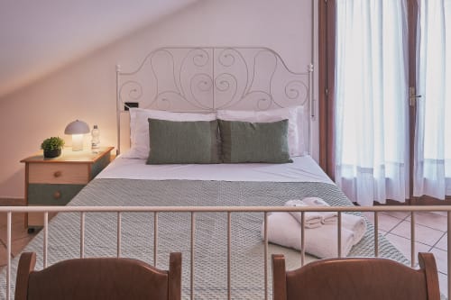Camera familiare Casa Mia B&B con testata ornamentale, vista balcone e scorcio di città tra le tende