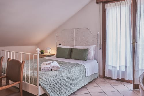 Camera familiare di Casa Mia B&B con letto in ferro battuto, cuscini verdi e accesso al balcone in stile italiano