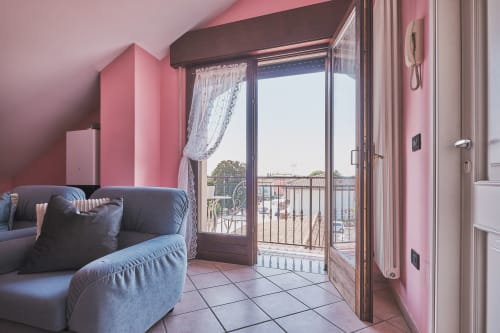 Elegante zona living con pareti rosa, divano grigio e porta-balcone in vetro che affaccia sulla città presso Casa Mia B&B in Italia