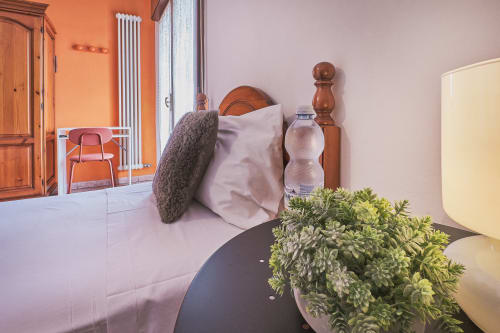 Accogliente camera di Casa Mia B&B con pianta grassa, cuscini, bottiglia d'acqua e arredi in legno con vista sulla città
