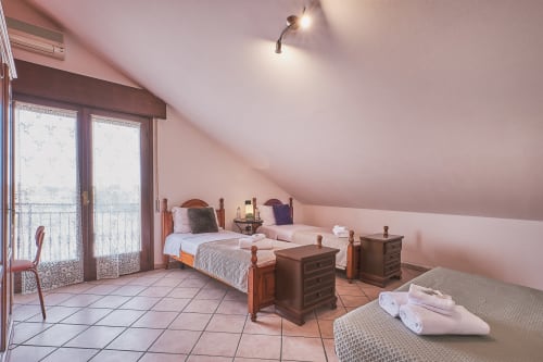 Ampia camera familiare a Casa Mia B&B con letti gemelli, balcone, pareti rosa e vista sulla città