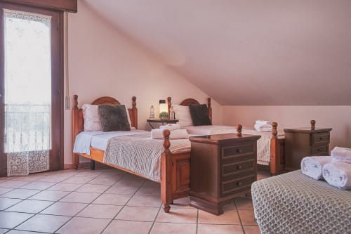 Spazioso camera familiare con letti gemelli, mobili in legno, pareti rosa e accesso al balcone - Casa Mia B&B