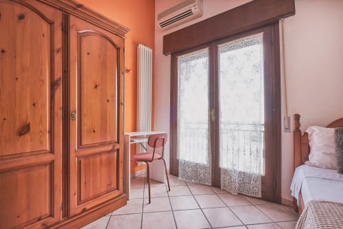 Luminosa camera familiare a Casa Mia B&B in Italia con armadio in legno, porte-finestre con vista sulla città e servizi moderni