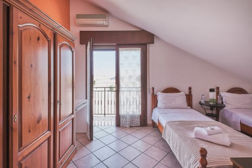 Camera familiare luminosa a Casa Mia B&B con letti gemelli, armadi in legno, accesso al balcone e vista sulla città in Italia