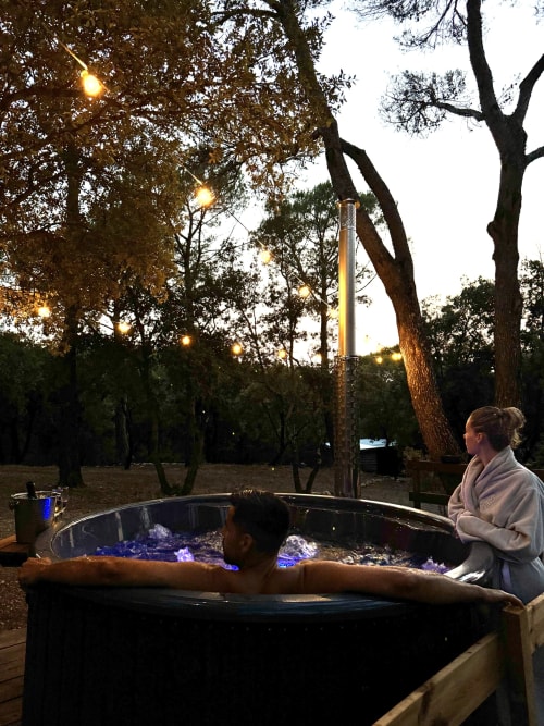 Les clients profitent d'un jacuzzi extérieur illuminé au Domaine d'Olga à Aniane, entouré d'arbres au crépuscule