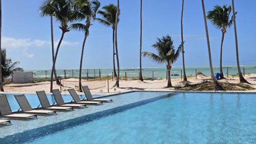 Piscina à beira-mar de Labedi Apartamentos com espreguiçadeiras, coqueiros e vista para o oceano da Praia de Ipioca em Maceió, Brasil