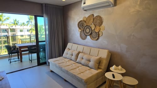 Área de estar moderna em Labedi Apartamentos em Maceió com sofá bege, arte decorativa e varanda com vista para o oceano