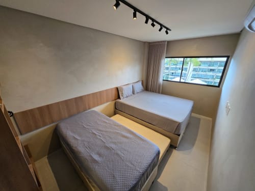 Duas camas de solteiro em quarto moderno do Labedi Apartamentos, Maceió, com vista para o oceano e móveis contemporâneos