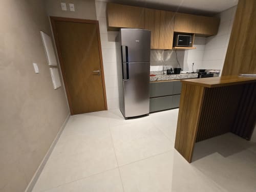 Cozinha moderna no Labedi Apartamentos, Maceió com eletrodomésticos de aço inoxidável, armários de madeira, bancada de granito e acabamentos brancos