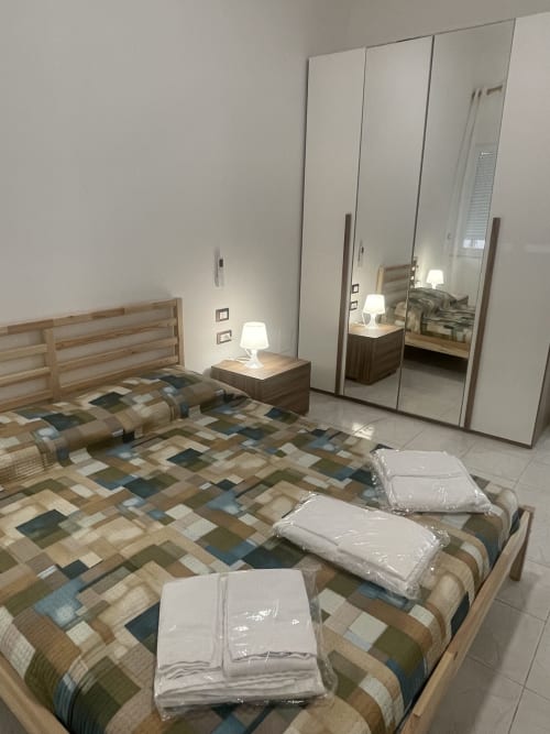 Camera moderna presso Rigiariloo Home Apartments a Termoli con armadio a specchio, letto in legno e biancheria confezionata