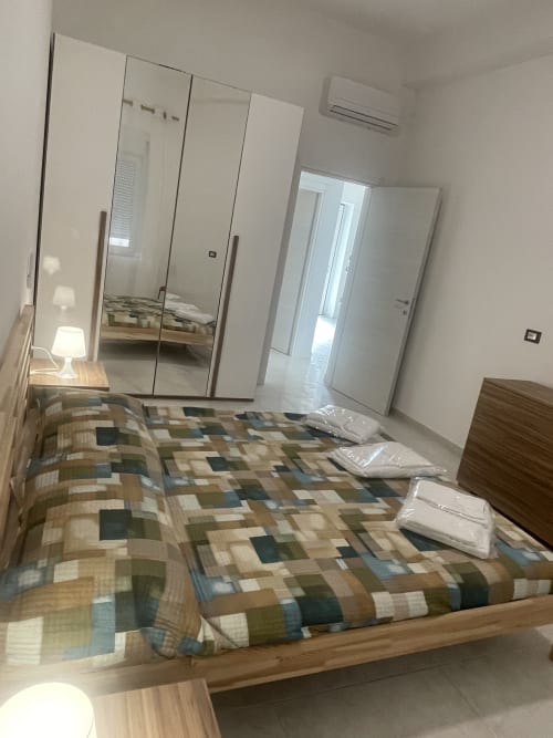 Camera moderna presso Rigiariloo Home Apartments a Termoli con armadio a specchio, biancheria a motivi e climatizzazione