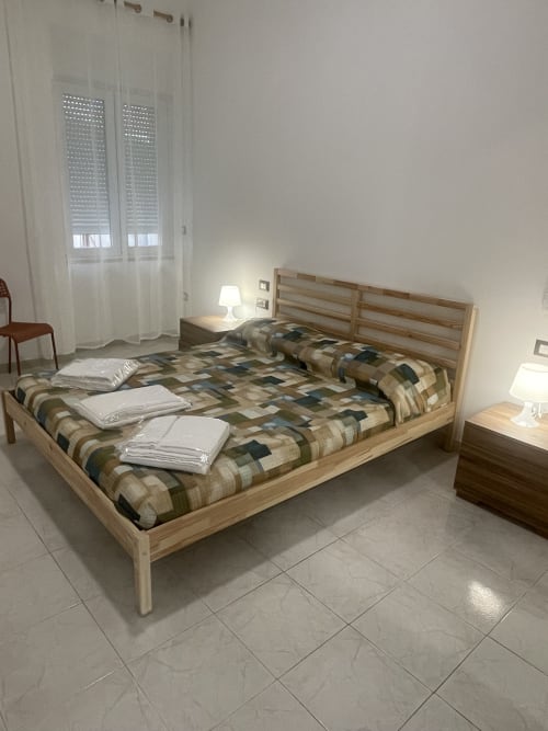 Camera luminosa a Casa Vacanze Nautilus a Termoli con letto in legno, biancheria scozzese e finestra con vista sulla città