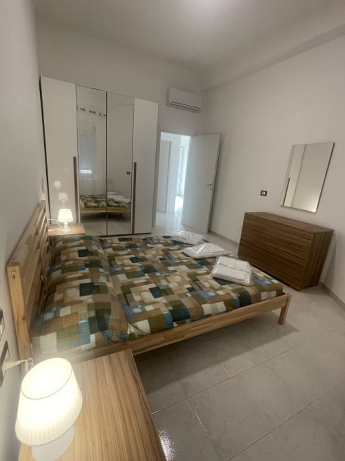 Camera moderna presso Rigiariloo Home Apartments a Termoli con letto in legno, guardaroba con specchio e climatizzazione