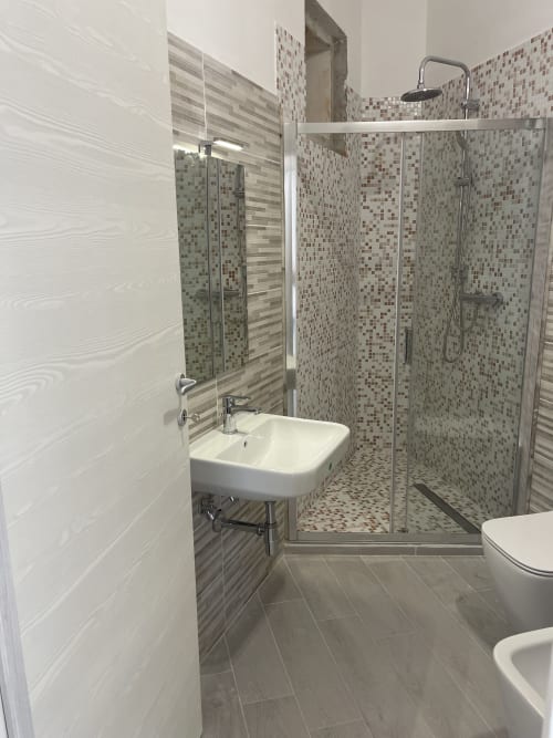 Bagno moderno nell'appartamento di Termoli con doccia in piastrelle mosaico, lavabo e wc