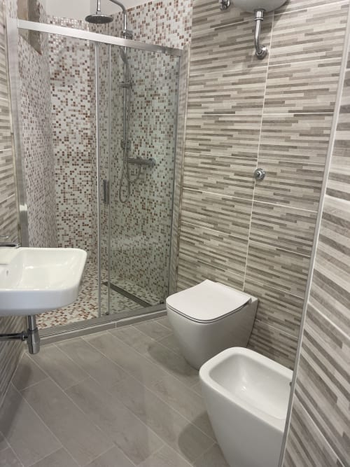 Moderno bagno con doccia passante, rivestimento in piastrelle mosaico e finiture contemporanee presso Rigiariloo Home Apartments a Termoli