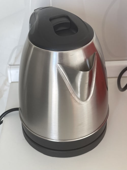 Bollitore elettrico in acciaio inox con coperchio e manico nero su bancone bianco presso Rigiariloo Home Apartments, Termoli