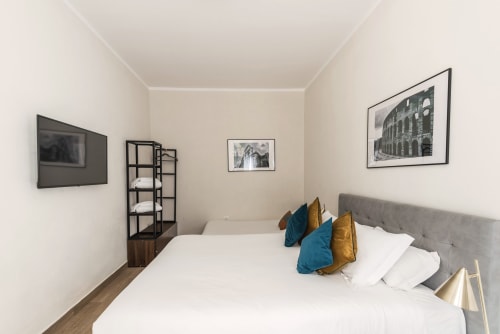 Camera moderna a Flavia's Holiday Home Roma con letto matrimoniale, cuscini blu e oro, opere d'arte, TV e libreria