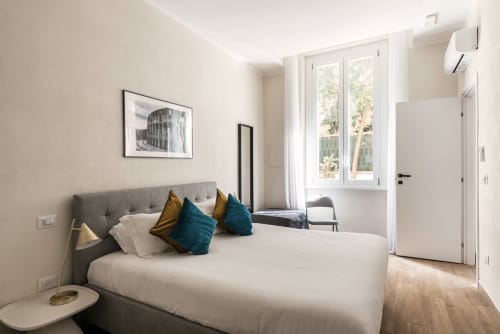 Camera da letto luminosa e moderna a Casa Vacanze di Flavia a Roma con letto grigio, cuscini turchesi e vista sul giardino