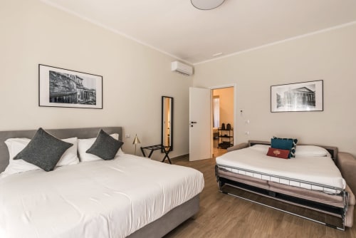 Ampia camera matrimoniale a Flavia's Holiday Home a Roma con due letti, arredamento moderno e quadri incorniciati