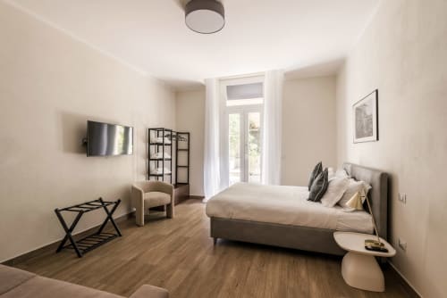 Camera moderna in Flavia's Holiday Home a Roma con letto, TV, poltrona e porte-finestre sul balcone