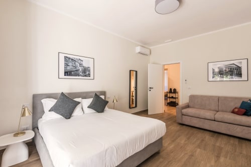 Studio moderno a Roma con letto matrimoniale, testata grigia, divano, pavimenti in legno e quadri con vedute della città