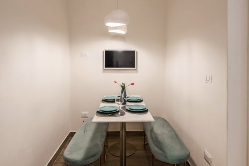 Moderna sala da pranzo di Flavia's Holiday Home a Roma con tavolo apparecchiato, lampada a sospensione e TV a parete