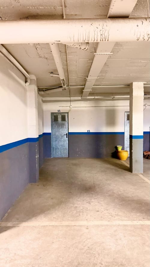 Garaje de estacionamiento subterráneo del hotel BH Marbella con paredes de rayas azules y blancas, piso de hormigón y espacios numerados