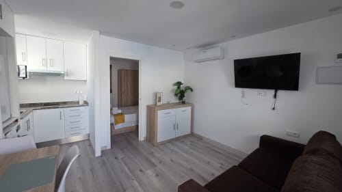 Moderno estudio en Benicàssim con cocina americana, sala, sofá, televisión y vista al dormitorio