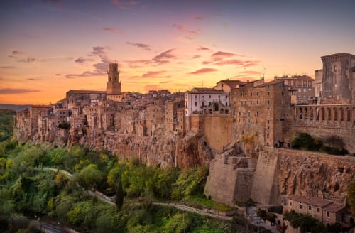 Villaggio medievale di Pitigliano al tramonto con edifici storici in pietra arroccati su scogliere, vicino a Canino, Italia