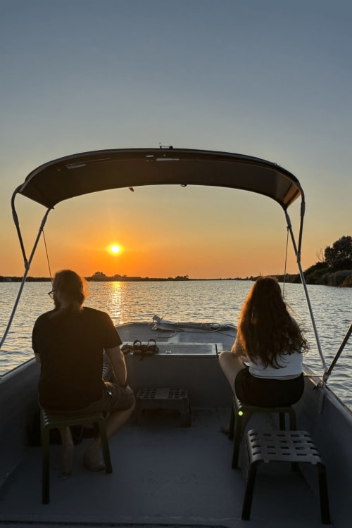 Due ospiti godono del tramonto da una barca vicino a Casa Mia B&B a Porto Viro, Italia