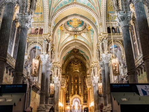 Interior de catedral ornamentada con arcos dorados y columnas en Lyon, Francia