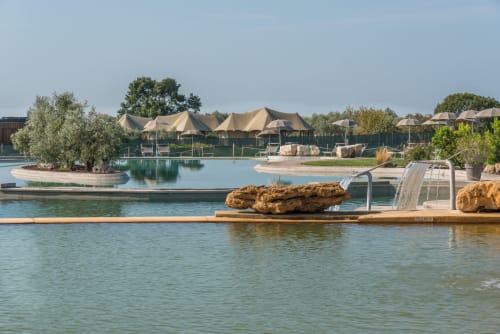 Piscina nella laguna di Il Poggio di Musignano con ombrelloni beige e aree relax a Canino, Italia