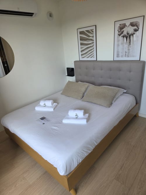 Chambre moderne de l'hôtel Les Loges De La Mer à Pérol, avec tête de lit grise, linge blanc et tableaux encadrés sur murs blancs