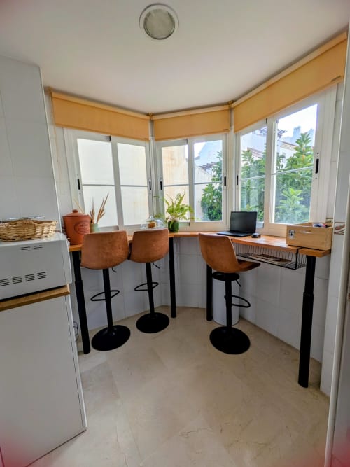 Espacio de coworking moderno en BH Marbella con barra, escritorios de madera y amplias ventanas con vistas a los jardines