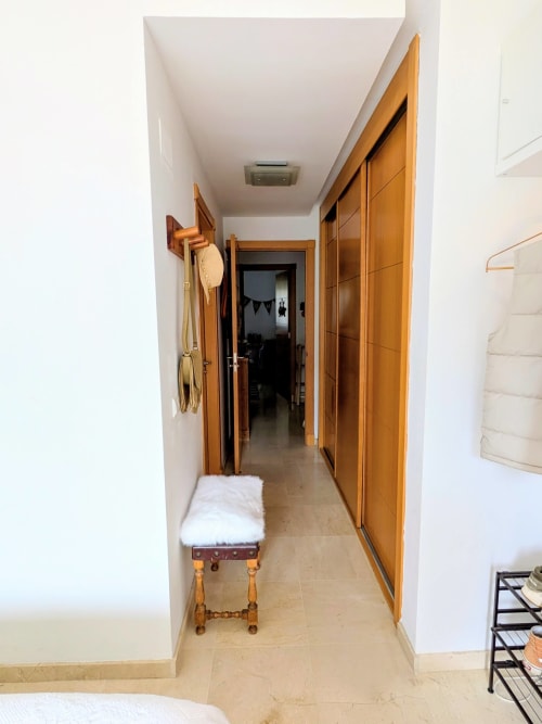 Pasillo moderno del hotel BH Marbella con puertas de armario de madera, suelo beige y paredes blancas
