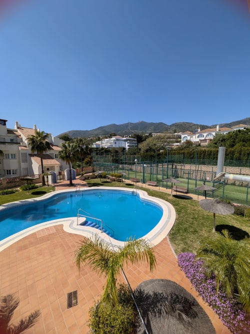 Piscina del resort BH Marbella con tumbonas, cancha de tenis y vistas a las montañas en España