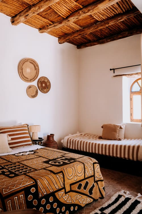 Chambre de style ethnique à l'hôtel Eucalyptus d'Essaouira avec poutres en bois, paniers tressés, textiles motifs et décoration naturelle
