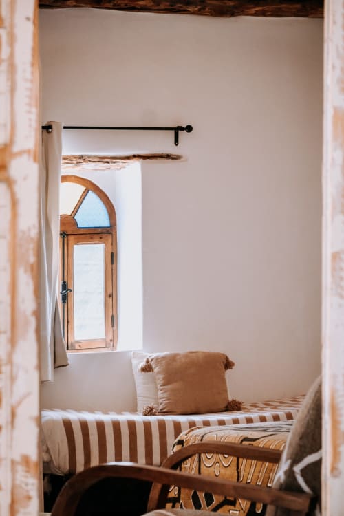 Chambre douillette à l'hôtel Eucalyptus Ethnic à Essaouira avec literie rayée, fenêtre en bois et décor rustique