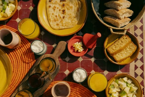 Petit-déjeuner marocain traditionnel à l'hôtel Eucalyptus avec pain plat, pâtisseries, fruits frais, jus et condiments locaux
