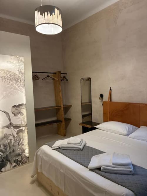 Camera matrimoniale moderna a Casa Città B&B a Brescia con letto in legno, lampada a sospensione, cabina armadio e arte botanica alle pareti