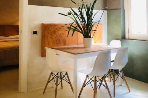 Zona pranzo moderna presso Casa Città Brescia con sedie bianche, tavolo in legno e pianta in vaso accanto alla finestra