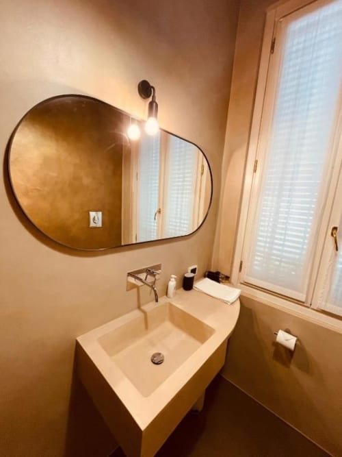 Bagno moderno di Casa Città a Brescia con specchio rotondo a muro, lavabo in marmo e illuminazione LED