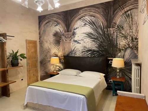 Deluxe Triple Room a Casa Città Brescia con letto in pelle nera, murale tropicale con palme, lampade gemelle e arredi moderni