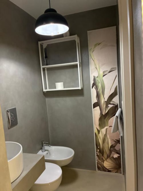 Bagno moderno della Casa Città Brescia BnB con lavabo bianco, water, bidet, illuminazione a sospensione e opere botaniche in doccia